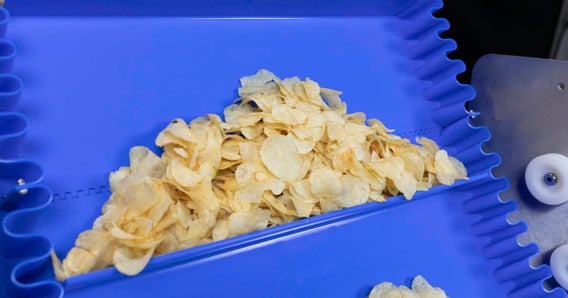 Tapis incliné ThermoDrive avec taquets et flancs synchronisés transportant des chips de pomme de terre