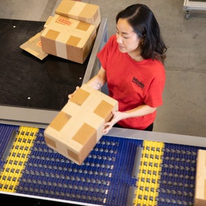 Woman in red t-shirt loading box onto ARB AutoPitch Induction