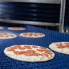 Pepperoni pizzas exiting a DirectDrive Stacker conveyor