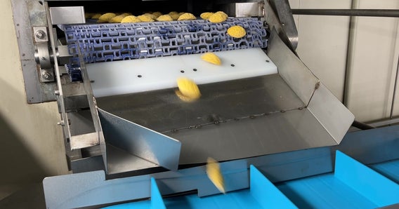 Omeletes em miniatura saem de um freezer em espiral e descem pela calha até uma esteira com taliscas