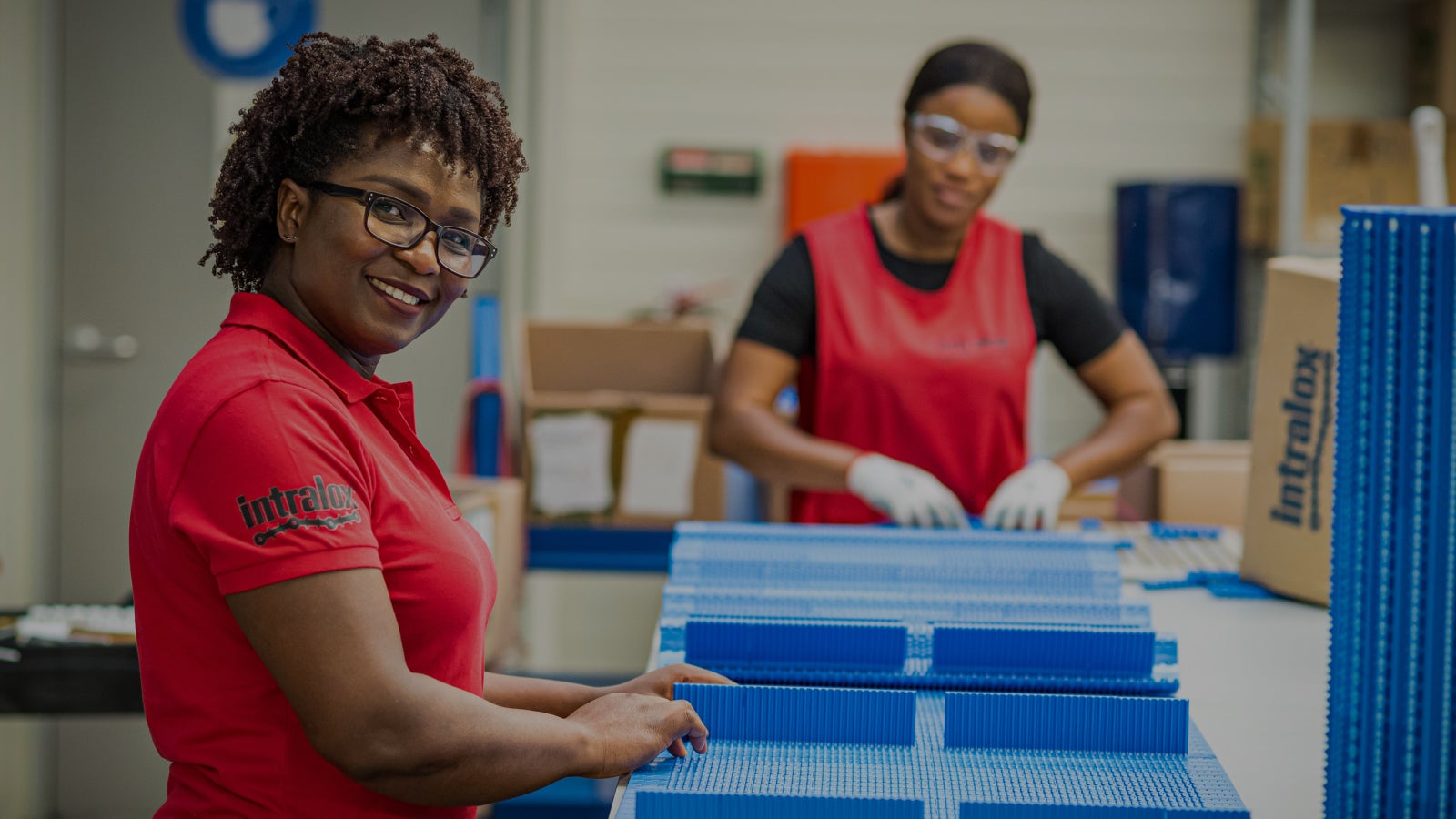 Two women in red uniforms assembling a conveyor belt