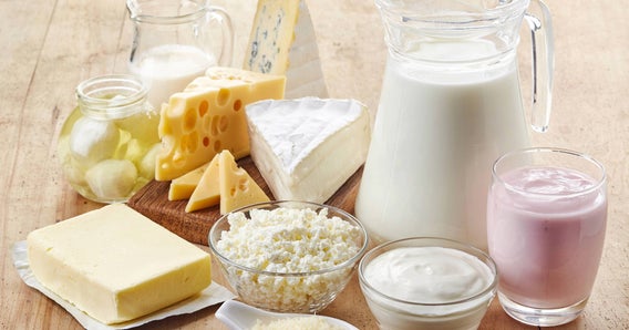 Prodotti caseari e bevande assortiti su un tavolo di legno. Include formaggi, yogurt, burro e latte.