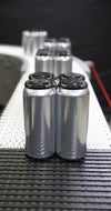 Four pack of aluminum cans crossing radius conveyor belt tight transfer