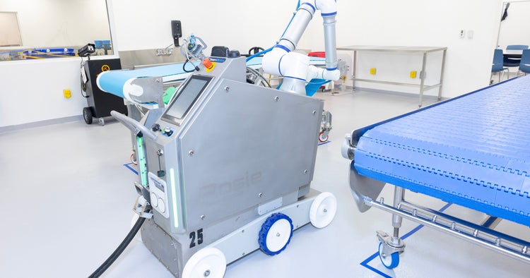 CleanBotix robot, “Rosie,” which automates the hose work in wet cleaning, positioned next to a conveyor