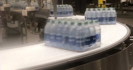 Casi di bottiglie d’acqua su nastro trasportatore curvo