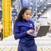 Female assembly worker holding laptop in warehouse