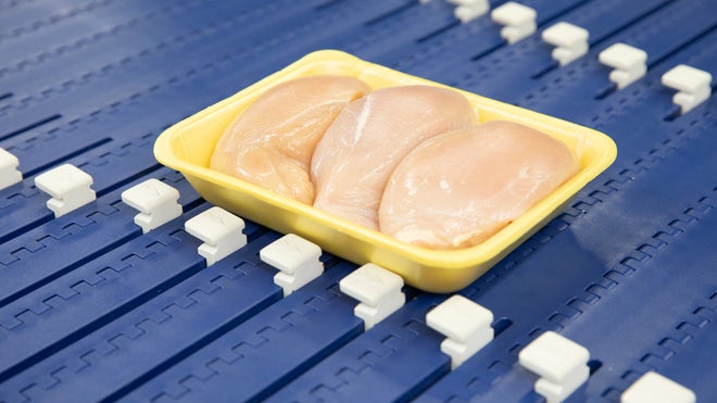 Paquete de bandejas de pechugas de pollo en el transportador AIM