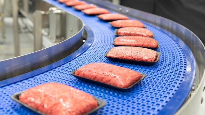 Paquetes de bandejas retractiladas de carne picada que se curvan alrededor de un transportador radial con bandas S2400 Heavy Duty Edge