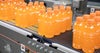 Ośmiopaki pomarańczowego napoju izotonicznego transportowane na przenośnikach