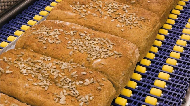 Loaves of seeded wheat bread on roller top belt