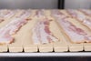 Tranches de bacon non cuites sur le tapis transporteur Série 900 Raised Rib Heavy Duty Edge
