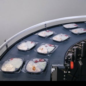 Sealed ready meal tray packs on Intralox Series 2100 ZERO TANGENT RADIUS conveyor belt