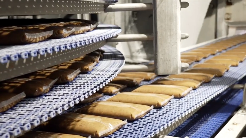 Pouched ready-to-eat side dishes moving along a DirectDrive System spiral freezer conveyor