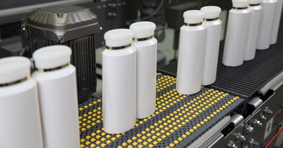 Shampoo bottles on conveyor with insert rollers