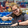 Female worker with glasses in gray shirt using belt puller on conveyor belt