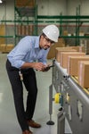 Worker inspecting packaging conveyor with boxes