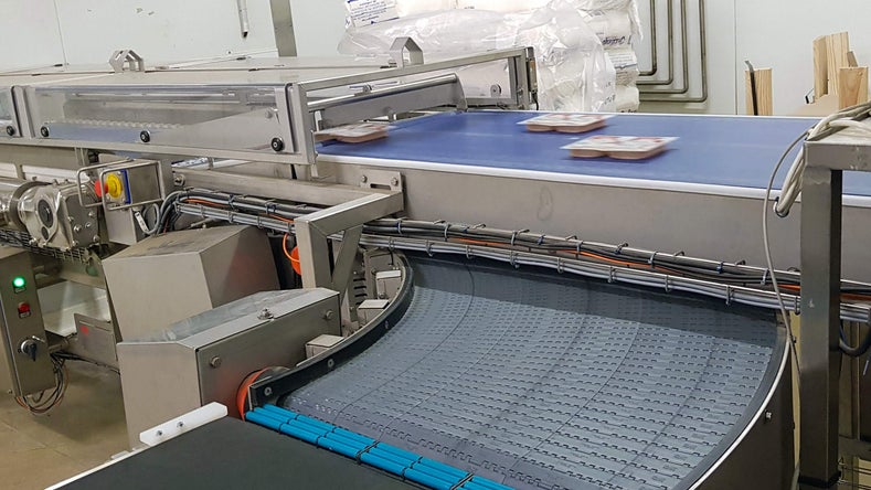 Diviseur AIM acheminant des barquettes de viande vers le tapis transporteur Intralox Série 2100 ZERO TANGENT