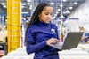 Female assembly worker holding laptop in warehouse