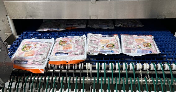 Le simili-crabe sort du nouveau système en spirale Intralox MPB de Trans-Ocean Products et est acheminé sur un tapis transporteur en plastique.