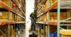 Worker on scissor lift examining warehouse shelves to fulfill an order