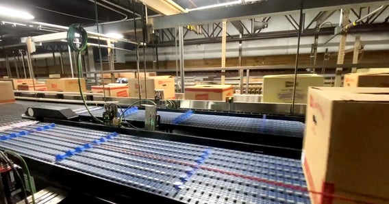 Sistema transportador automatizado clasificando paquetes de aperitivos de Herr's en una planta altamente eficiente, dotado de tecnología avanzada de packaging y logística.