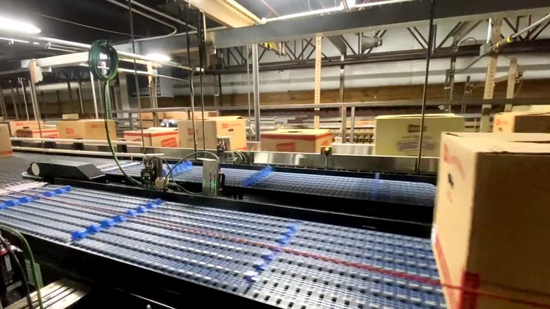 Sistema transportador automatizado clasificando paquetes de aperitivos de Herr's en una planta altamente eficiente, dotado de tecnología avanzada de packaging y logística.