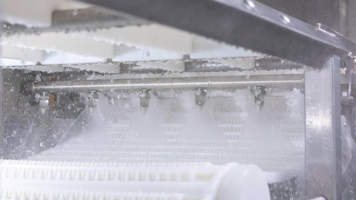 Intralox Clean-In-Place Spray Bar spraying water onto white conveyor belt