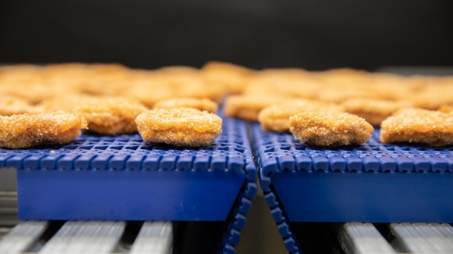 Nuggets de pollo empanados en un transportador de transferencia estrecha