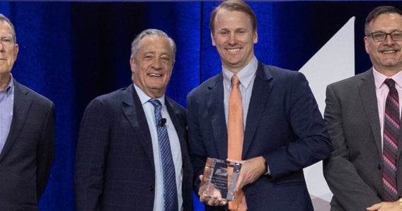 Two men in suits holding award while posing for photograph