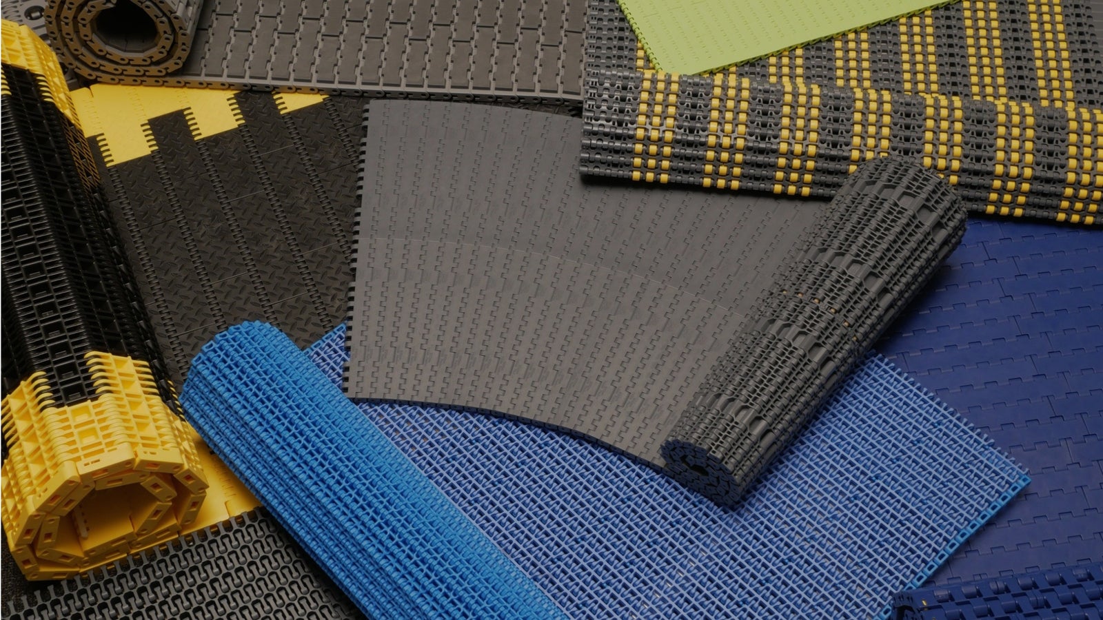 An array of Intralox modular plastic conveyor belts, in a variety of colors, arranged artistically in stacks and rolls