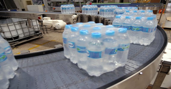Shrink-wrapped bundles of bottled water rounding radius conveyor