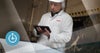 Worker with hairnet holding computer tablet; clock uptime icon