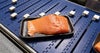 Paquete de bandejas con filete de salmón en porciones en el transportador AIM