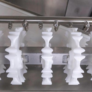 Drei weiße CleanLock-Zahnräder auf einer Welle mit Clean-in-Place-Sprühleiste