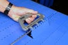 Hand holding Intralox Belt Puller threaded through conveyor belt hinge