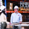 Man and woman in hardhats standing next to conveyors in warehouse