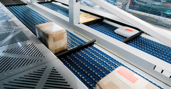 Packages on blue roller conveyors guarded by plexiglass