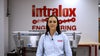 A woman (Erin Oakes) standing in front of a red and white sign that says "Intralox Engineering." She has shoulder-length brown hair and is wearing a blue shirt with a red Intralox logo.