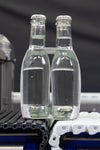 Botellas de vidrio transparente con líquido transparente en una cinta transportadora