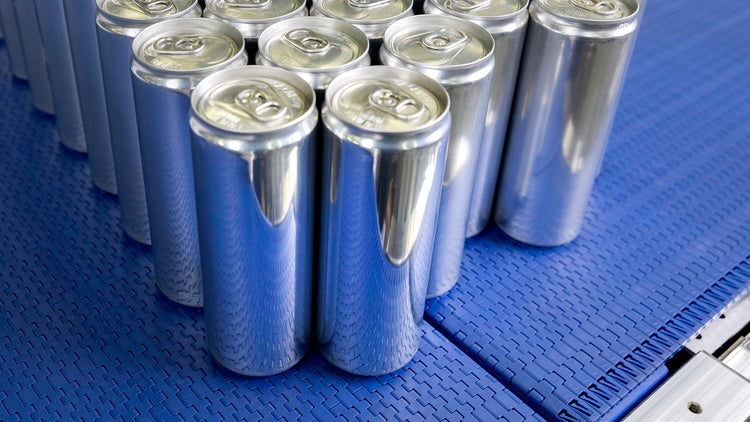 工厂内,蓝色传送带上正在输送一组易拉罐饮料。