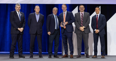 A group of men in suits receives award