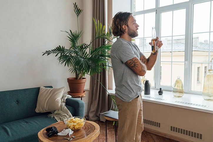 A man drinking a bottle of beer in his living room