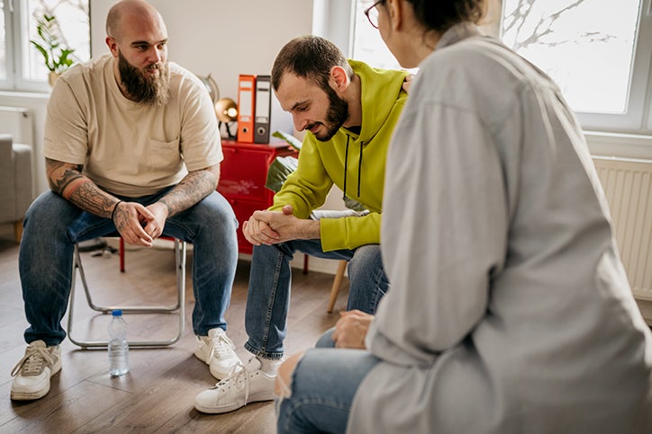 A picture of a man receiving professional counselling support from a fellow participant and a professional