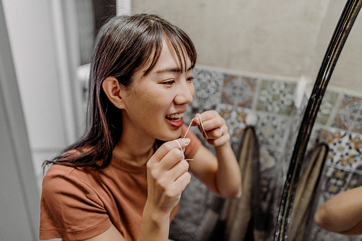 A woman flosses her teeth