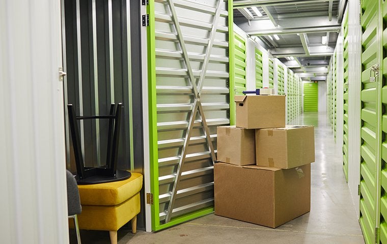 Storage facility with a units door open with boxes and furniture being stored