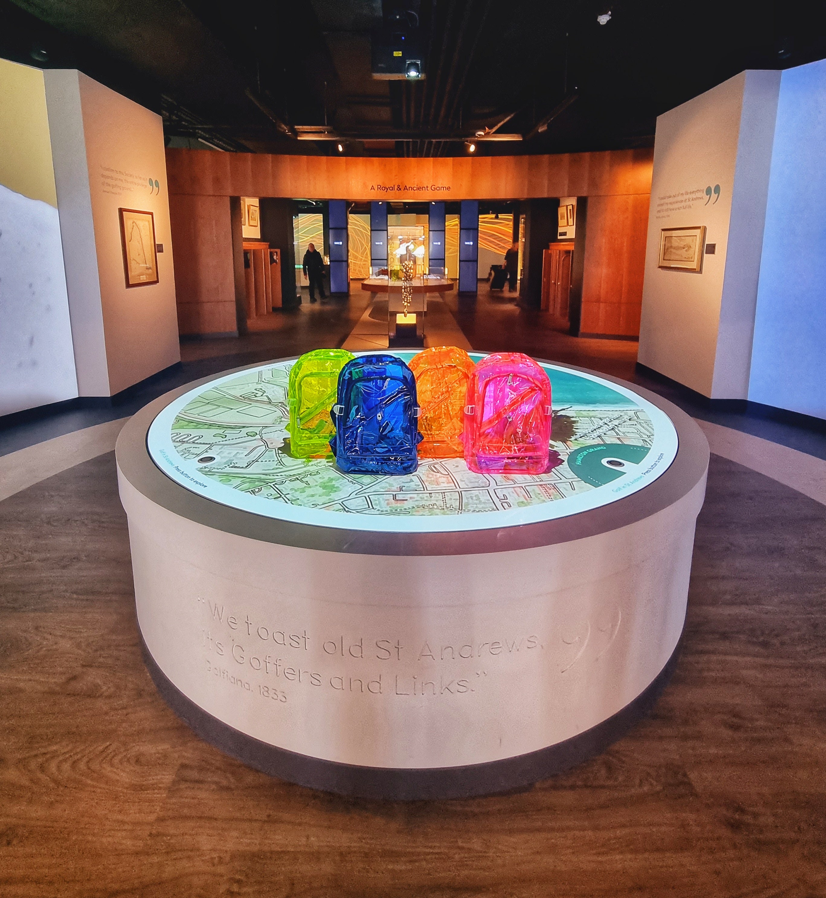 Four bright colourful backpacks sit on the interactive map table in the centre of the museum galleries.