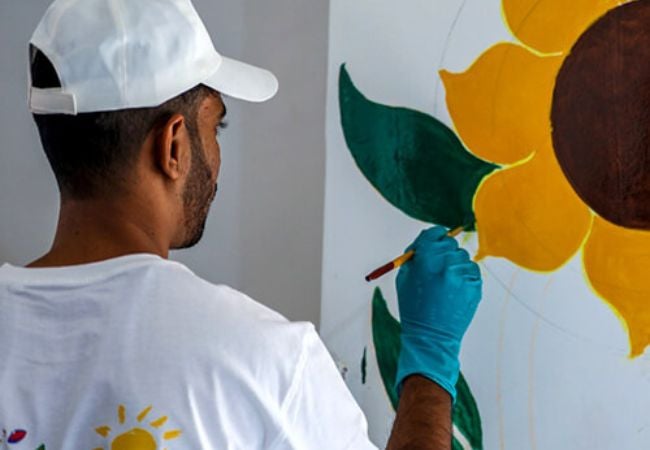 man painting sunflower mural in Gujarat, India 