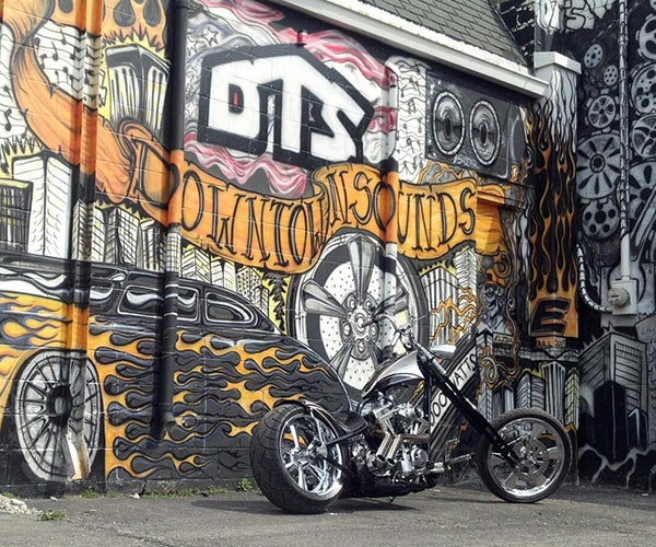 Motorbike parked next to large mural on building