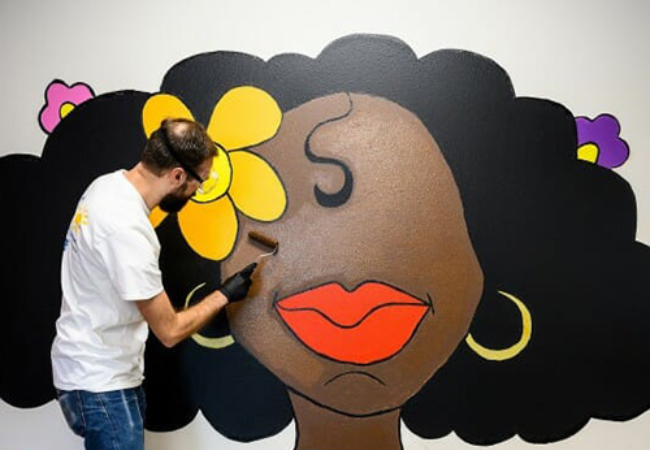 man painting mural of girl with flowers in her hair in Madison, Wisconsin 