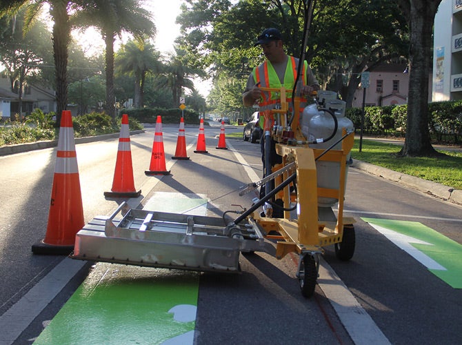 Worker applying coatings to a roadway.